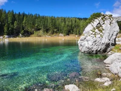 A clear turquoise mountain lake with a large boulder