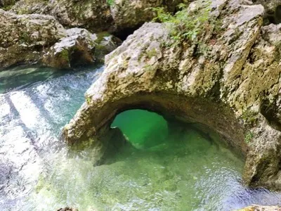 A rock arch over clear green water